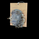 graue Maske aus Pappmaché mit Federschmuck auf Holzbrett